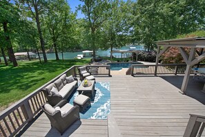 Eine Terrasse mit Gartenmöbeln, einem Pool und Blick auf einen See.