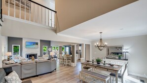 A spacious living area with a sofa, dining table, and chairs, a staircase, and a kitchen area. - Nights on Normandy (Mooresville)