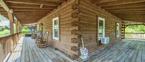 A log cabin with a covered porch, wooden flooring, and rocking chairs.
