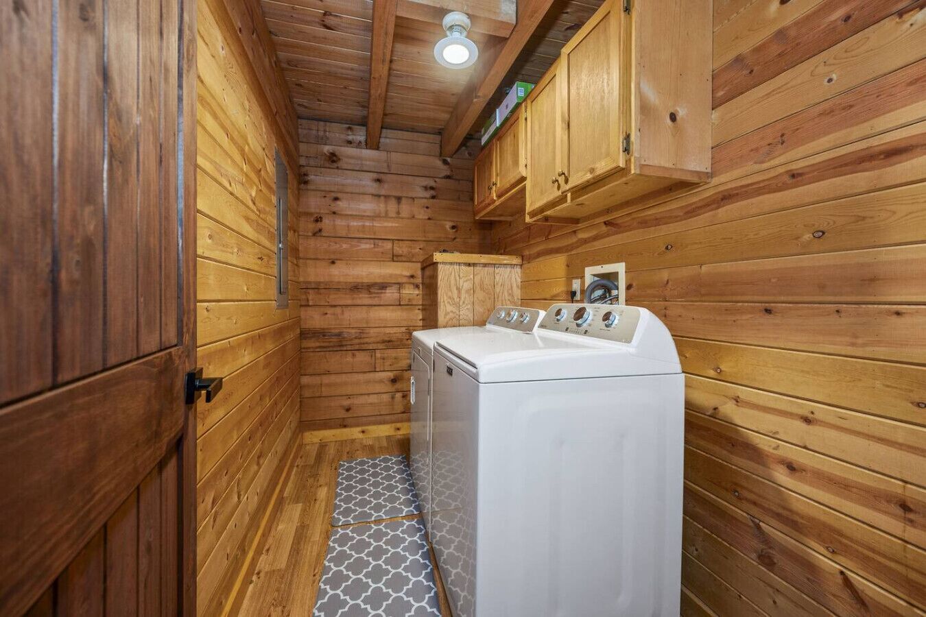 Ein kleiner Waschraum mit Holzwänden und einer weißen Waschmaschine.