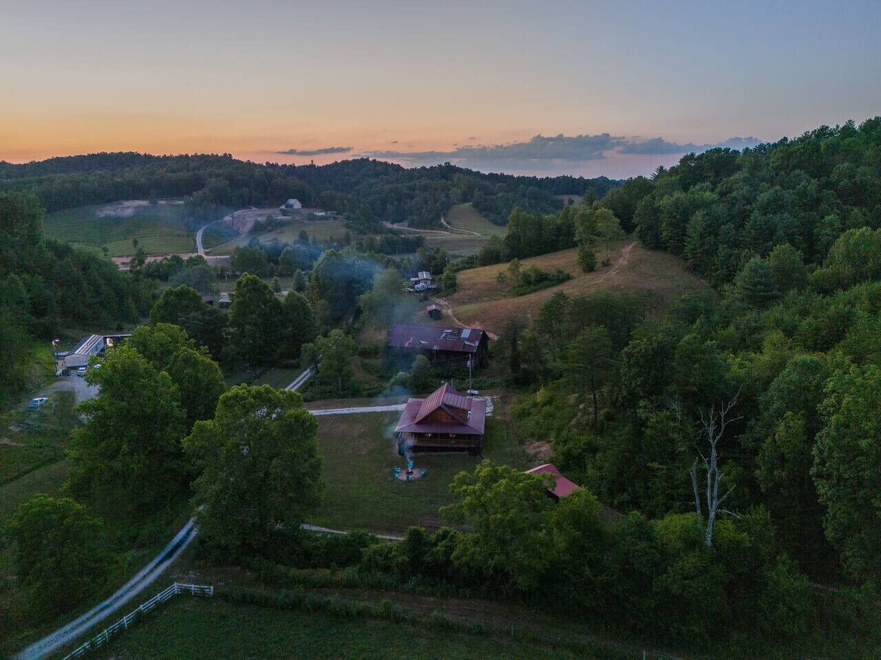 A rural landscape with a house surrounded by trees and fields.