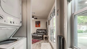 A laundry room with a washer and dryer, a hallway leading to a living area with a leather couch and a rug. - Cozy 1-bedroom Retreat in Tulsa (Tulsa)