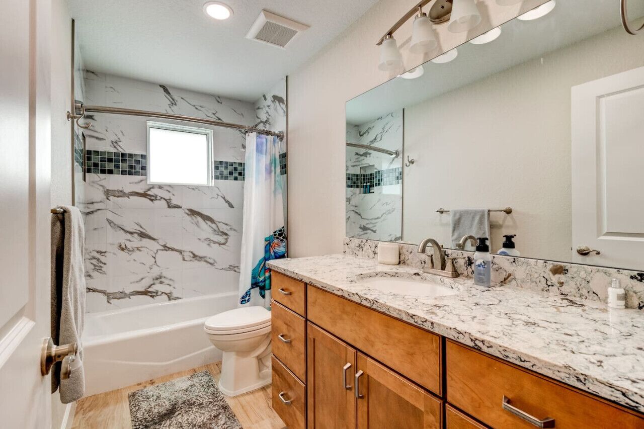 A bathroom with a shower, toilet, and vanity with a large mirror.