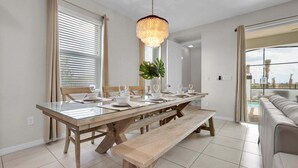 Ein Essbereich mit einem Glastisch, Holzbänken und einer Chandelüstere.