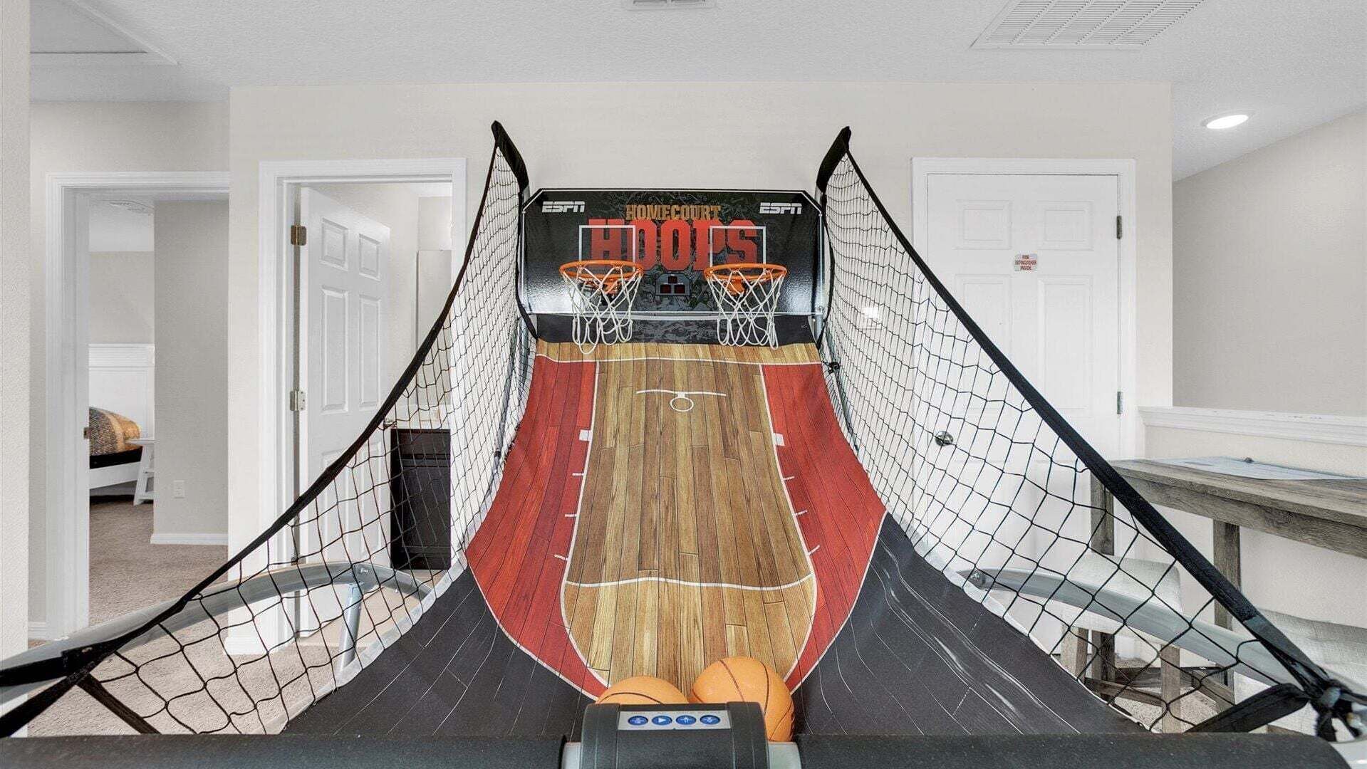 Een basketbalveld bij een huis, met een scorebord, houten vloer en net.