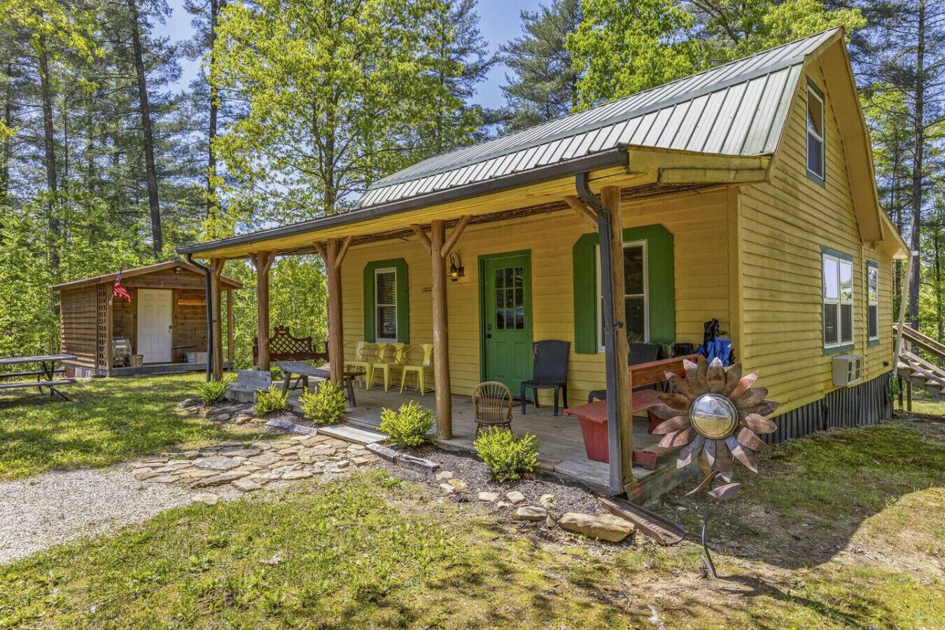 A rustic cabin with a porch, a small attached structure, and a stone pathway.