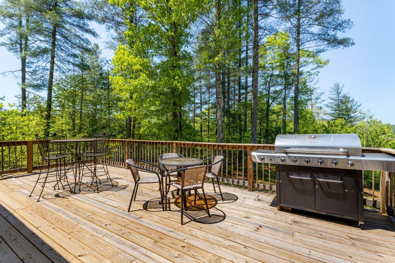 Een houten terras met een barbecue en tuinmeubilair.
