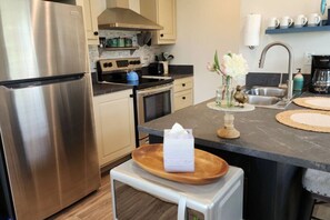 A modern kitchen with stainless steel appliances, a wooden island, and a vase with flowers. - Wifi, Firepit, Fishing Pond - Farmview (Hazel Green)