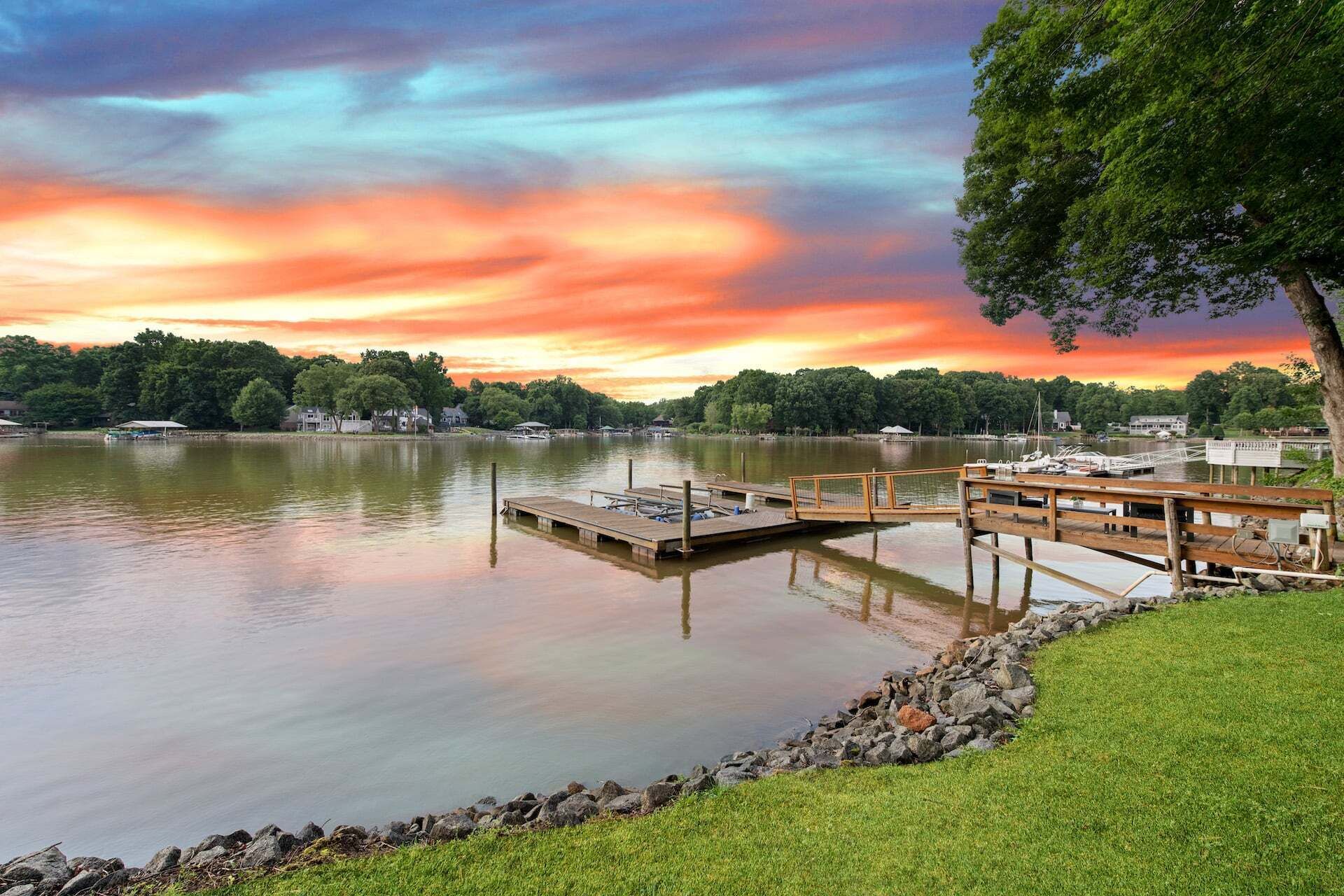 A lakeside view with a dock, grassy area, and trees.