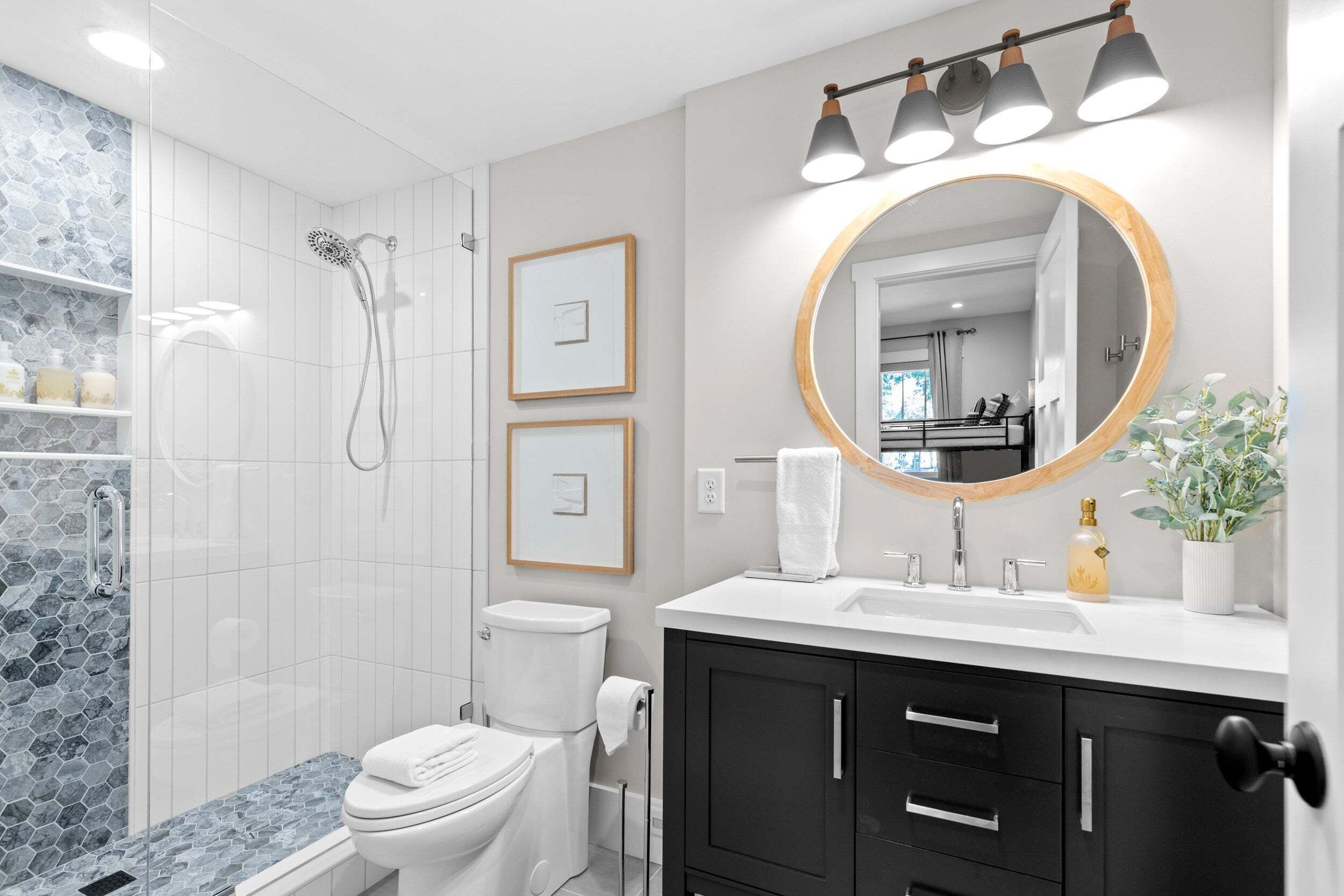 A modern bathroom with a shower, toilet, vanity, and a large mirror.