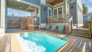 A pool area with wooden deck, lounge chairs, and a hot tub. - The Oyster House - Pet Friendly! Golf Cart Included! (Port Aransas)