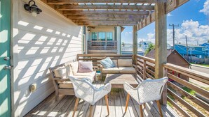 A wooden deck with a sofa, two chairs, and a small table. - The Oyster House - Pet Friendly! Golf Cart Included! (Port Aransas)