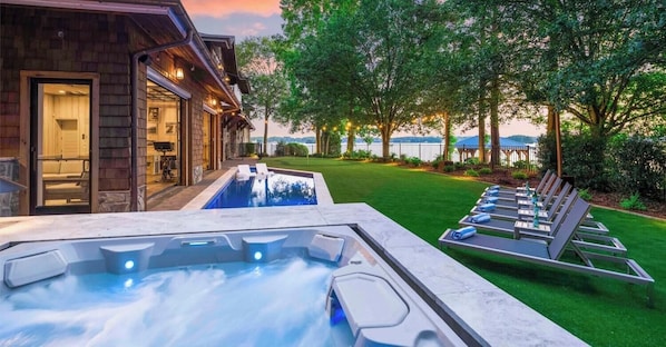 A hot tub with a view of a pool and a deck with lounge chairs. - The Chasestone (Mooresville)