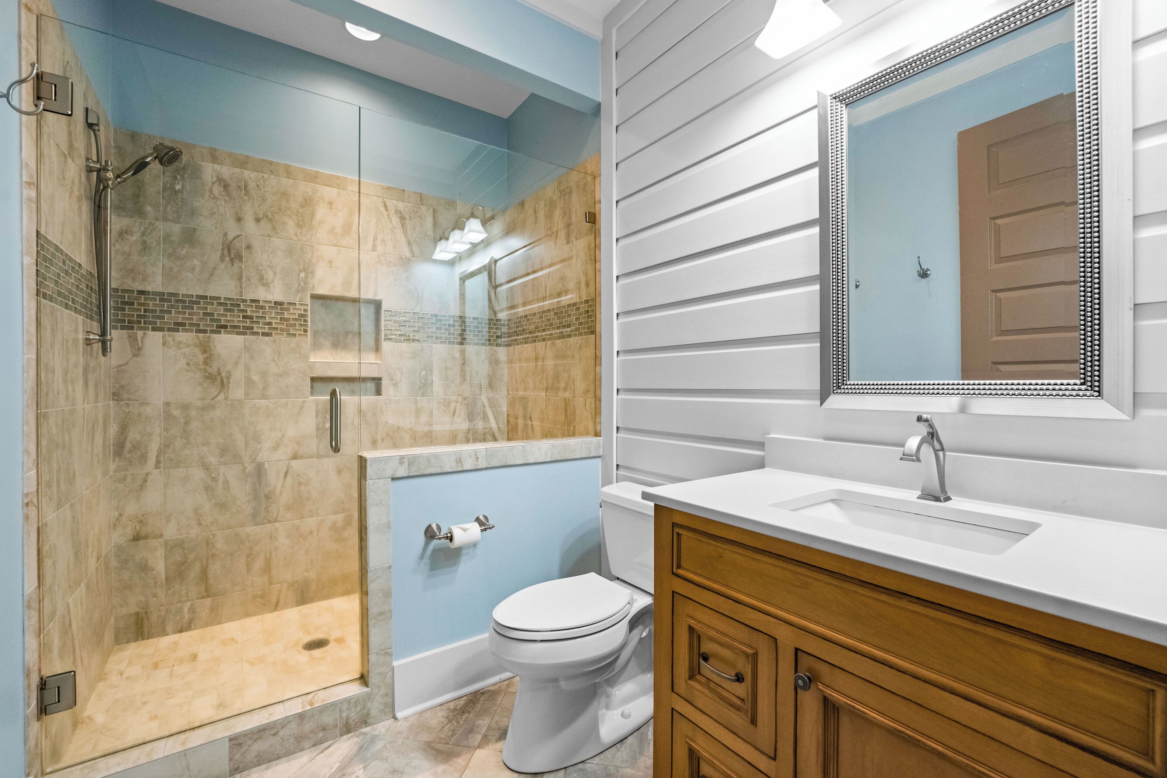 Une salle de bain avec une douche à l’italienne, des toilettes et un meuble-lavabo avec un miroir.