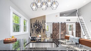 A modern kitchen with a black marble countertop, a built-in sink, and a wooden accent wall. - Two Tree Houses - Beehive & H20 (Pittsboro)