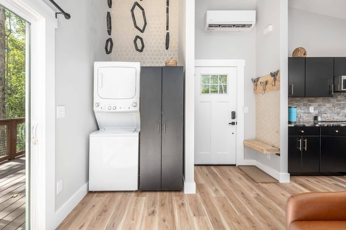 A compact kitchen with a washer and dryer, a white door, and a black countertop.