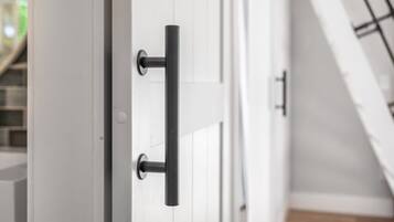 A white door with a black handle and a keyhole, part of a room with white walls and a wooden floor.