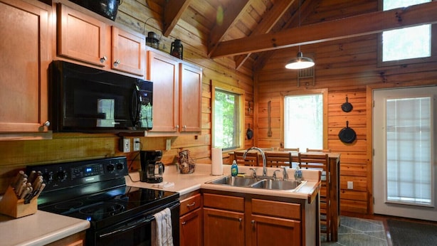 A wooden cabin kitchen with a stove, microwave, and sink. - Hot Tub & Wifi - Hidden Chalet Red River Gorge, KY (Campton)