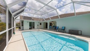 Una piscina interior con agua cristalina, rodeada por una zona techada con sillas y vistas al cielo.