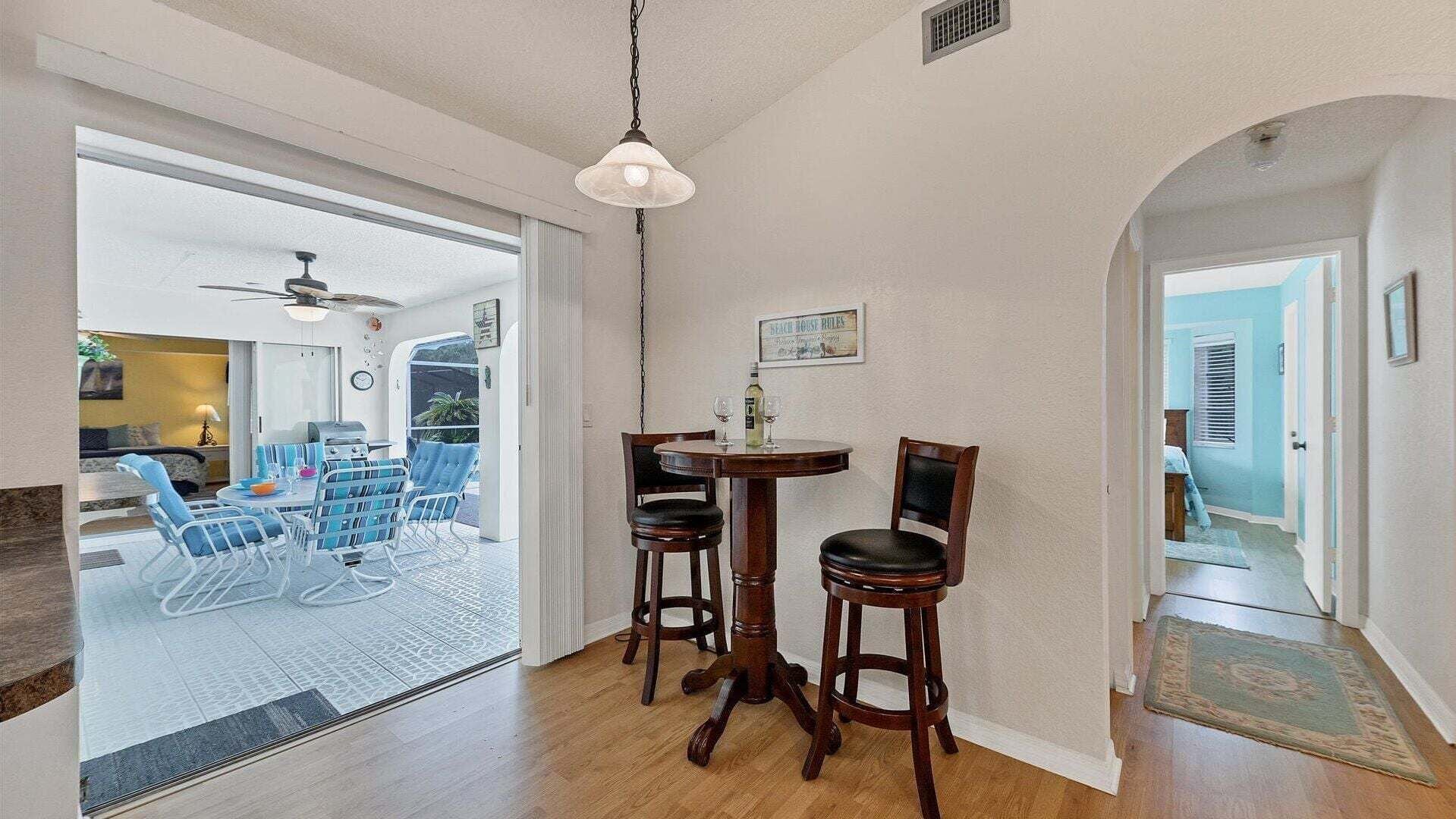 Un coin repas comprenant une table et des chaises, un ventilateur de plafond et une vue à travers une porte vitrée.