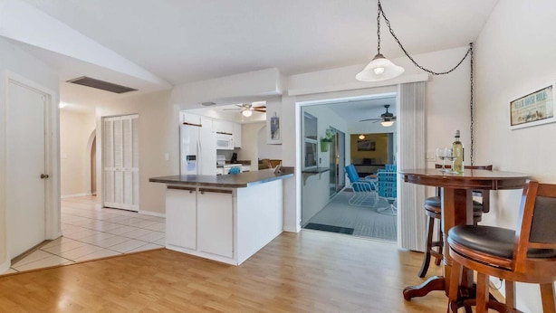 Una cocina moderna con armarios blancos, encimera de madera y una zona de comedor con mesa y sillas de madera.