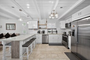 Een moderne keuken met witte kasten, roestvrijstalen apparatuur en een centraal eiland met barstoelen.