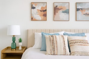 A neatly arranged bedroom with a bed, pillows, a nightstand, a lamp, and wall art. - Worker Friendly, Kingbed,washer Dryer, A+location, Wifi (Sherman)