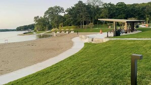 A park with a sandy beach, a grassy area, and a covered pavilion.