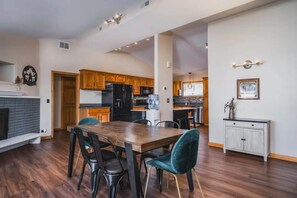 A spacious kitchen with wooden cabinets, a dining table with chairs, and a fireplace. - Meyers Bay Sunset Lakefront Cottage in Fox Lake w/ Boat Pier (Fox Lake)