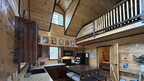 A spacious kitchen with wooden cabinets, a large island, and a dining area with a high ceiling and wooden beams. - Wifi & Hot Tub, Large Family - Climb On in Rrg! (Rogers)