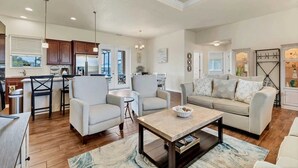 A spacious living area with a sofa, armchairs, a coffee table, and a kitchen in the background. - Mtd10333 (Port Charlotte)