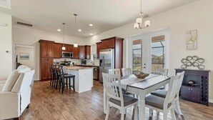 A spacious kitchen with wooden cabinets, a central island, and a dining area with white chairs. - Mtd10333 (Port Charlotte)