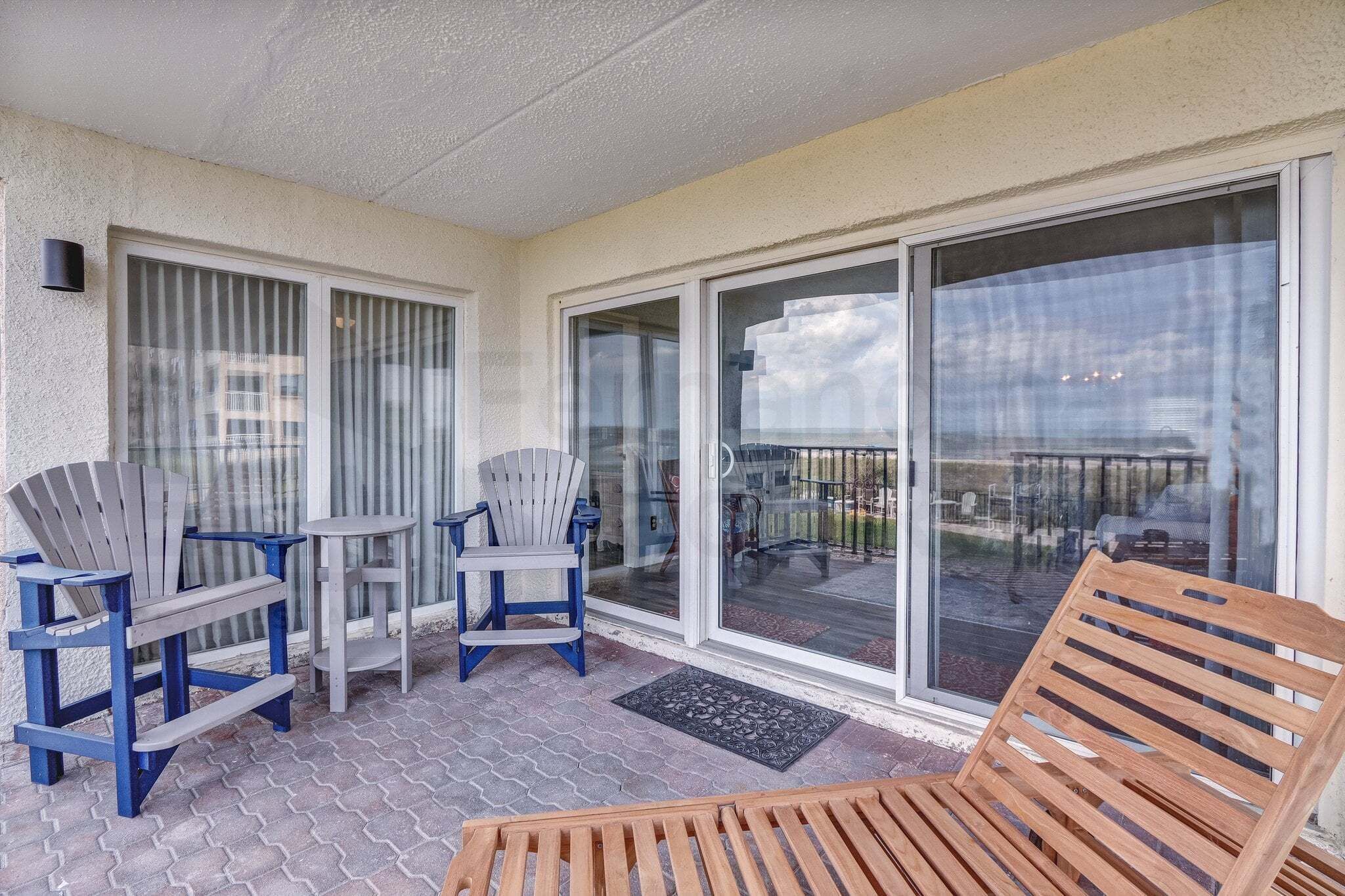 A covered patio with two Adirondack chairs, a small table, and a wooden bench.