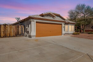 A single-story house with a garage, a satellite dish, and a wooden fence.