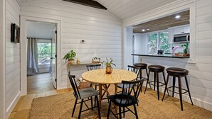Un comedor con una mesa redonda, sillas y una cocina al fondo.
