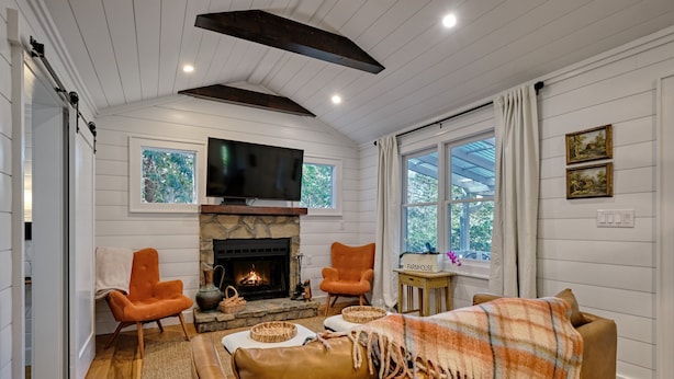 Una sala de estar acogedora con chimenea, dos sillones, un sofá y un televisor.