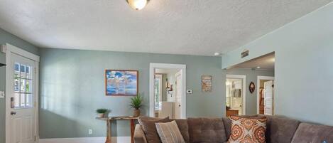 A living room with a couch, a small table, and a painting on the wall.