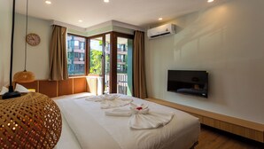 Ein Hotelzimmer mit einem großen Bett, einem Fernseher und einem Balkon mit Vorhängen.