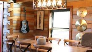 A rustic wooden interior with a dining table, chairs, a guitar, and decorative items. - Karaoke, Hot Tub, 1GB Wifi - The Rock House - LUX (Rogers)