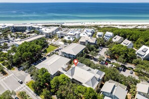An aerial view of a coastal residential area with modern buildings, a beach, and a marina.