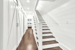 Ein modernes Interieur mit einer Holztreppe, weißen Wänden und einem Flur, der zu einem Schlafzimmer führt.