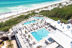 Ein Resort mit großem zentralen Pool, zahlreichen Liegestühlen und einem Strandbereich.