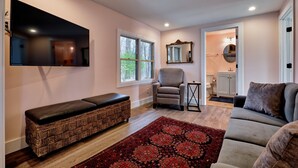 A living room with a bench, a sofa, a TV, a chair, and a patterned rug. - The Pink Lady (Highlands)