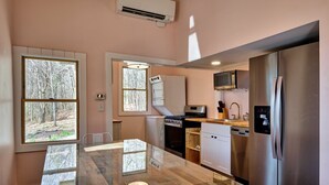 A modern kitchen with a glass dining table, stainless steel appliances, and large windows. - The Pink Lady (Highlands)