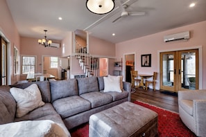 A living room with a grey sectional sofa, a red rug, and a ceiling fan. - The Pink Lady (Highlands)