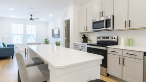 A modern kitchen with white cabinets, a microwave, an oven, and a coffee maker. - Gym, Pool, Washerdryer, Workerfriendly A+location (Sherman)
