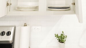 A kitchen with white cabinets, a stove, a roll of paper towels, and a small potted plant. - Gym, Pool, Washerdryer, Workerfriendly A+location (Sherman)