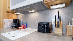 A kitchen with a microwave, toaster, coffee maker, and knife block. - Walkout Beachfront Condo: Pointes North Resort 106 (Traverse City)