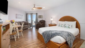 A bedroom with a wooden bed, a desk with a chair, a sofa, and a ceiling fan. - Walkout Beachfront Condo: Pointes North Resort 106 (Traverse City)
