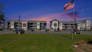 A hotel with multiple buildings, a parking lot, and an American flag. - Walkout Beachfront Condo: Pointes North Resort 106 (Traverse City)